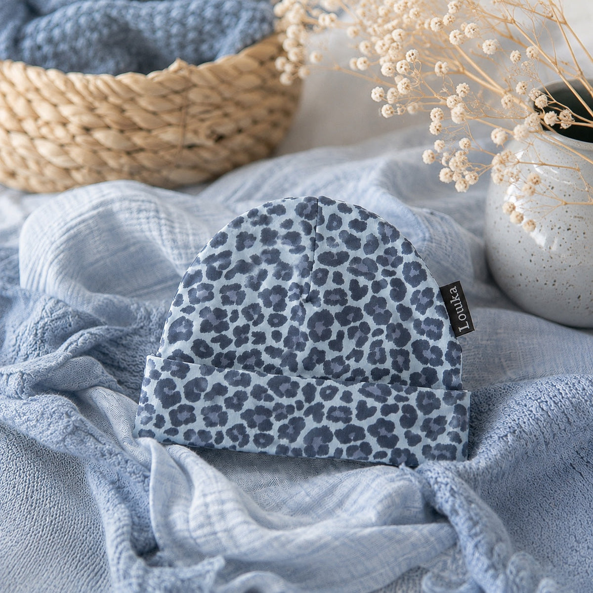 Louka newborn babymutsje met blauwe panterprint en omslagrand op blauwe babydoeken